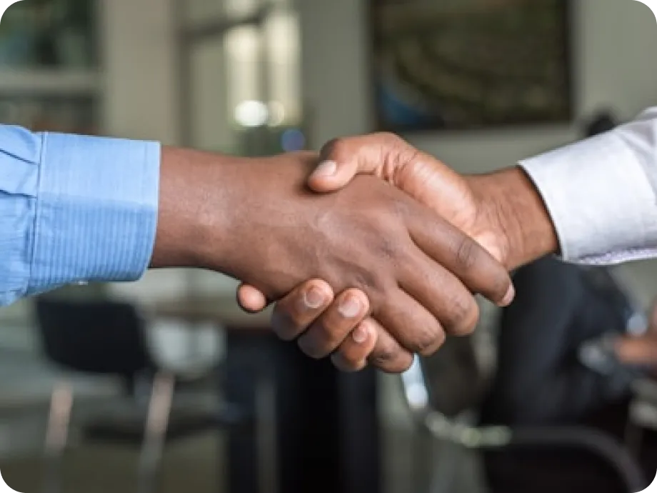 Two people shaking hands in a professional office setting.