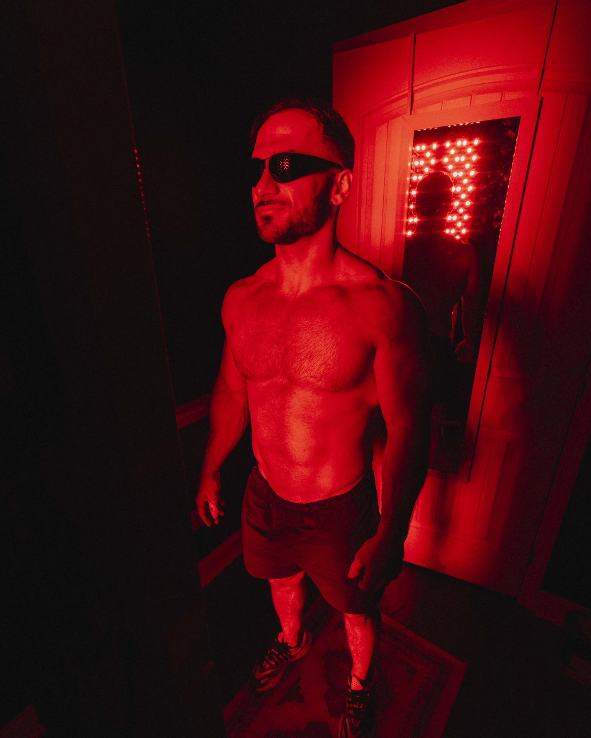 Hyperbaric House's red light therapy room in use - showing a man using the googles and panels and a body mirror.