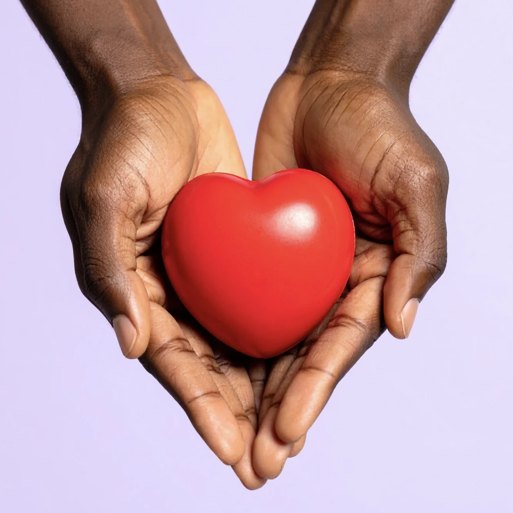A purple background with two hands cupping and holding a red heart.