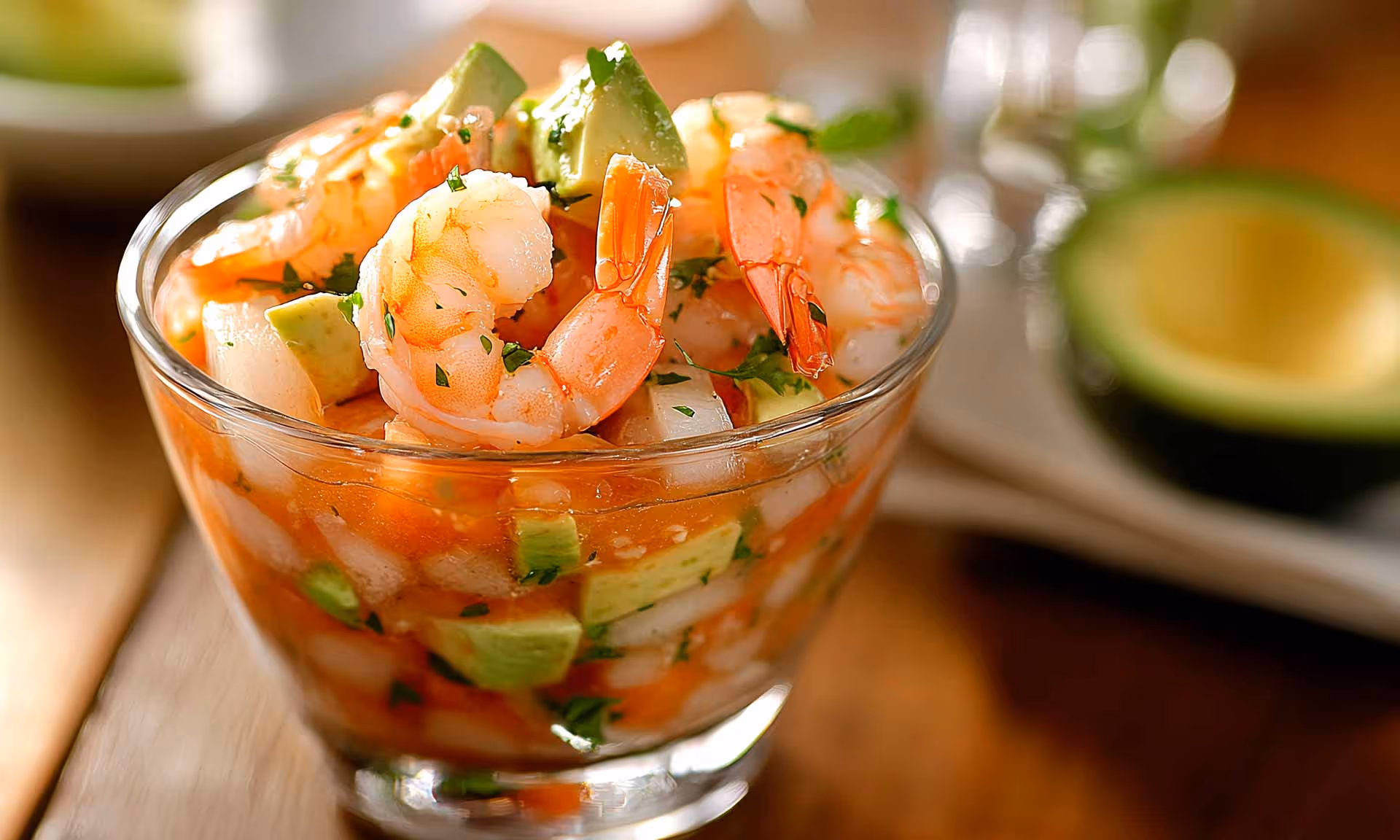 A glass bowl filled with shrimp and avocado.