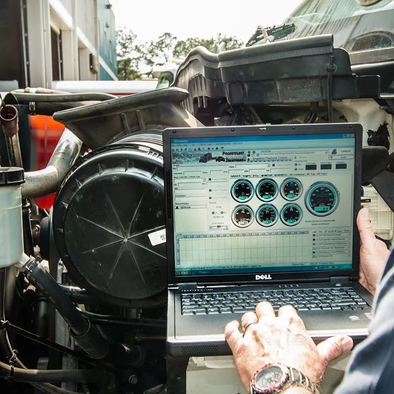Heavy-duty repair technician uses PF-Diagnose software on a Dell laptop to check truck diagnostics before a DOT inspection.