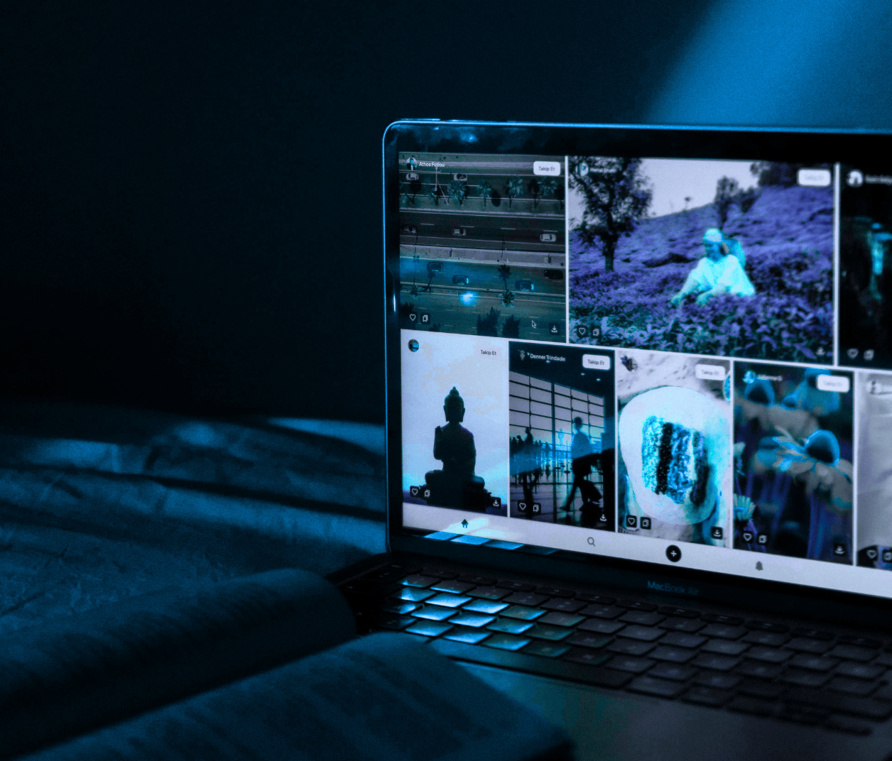 Vue d'un ordinateur portable ouvert dans un environnement sombre, affichant une mosaïque de contenus sociaux créatifs, symbolisant la gestion et l'animation de communauté.