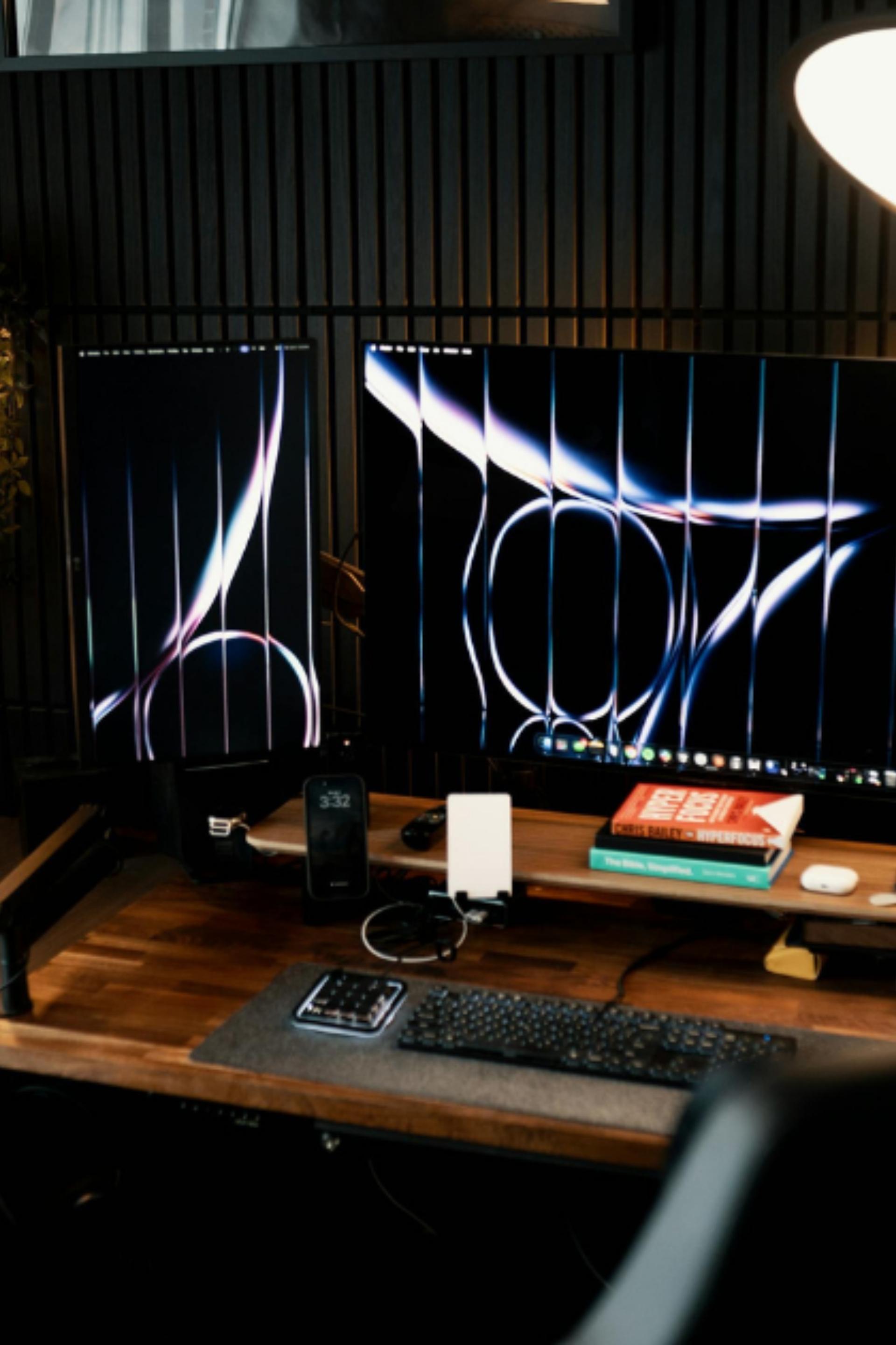 Poste de travail ergonomique et moderne avec deux grands moniteurs affichant des graphismes d'IA, un bureau en bois massif et une chaise gamer, symbolisant la productivité d'une agence web.