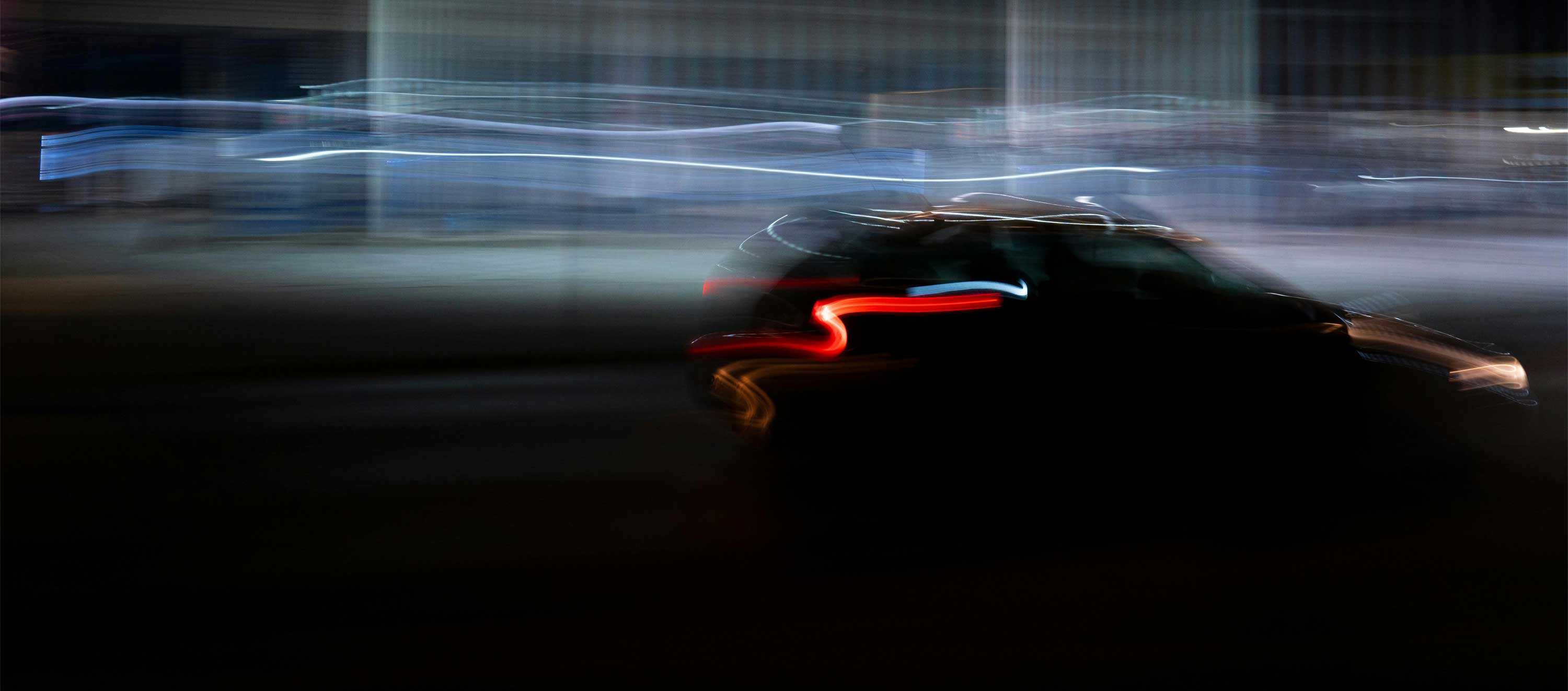 Blurred black car with visible red taillight streaks, captured in motion at night.