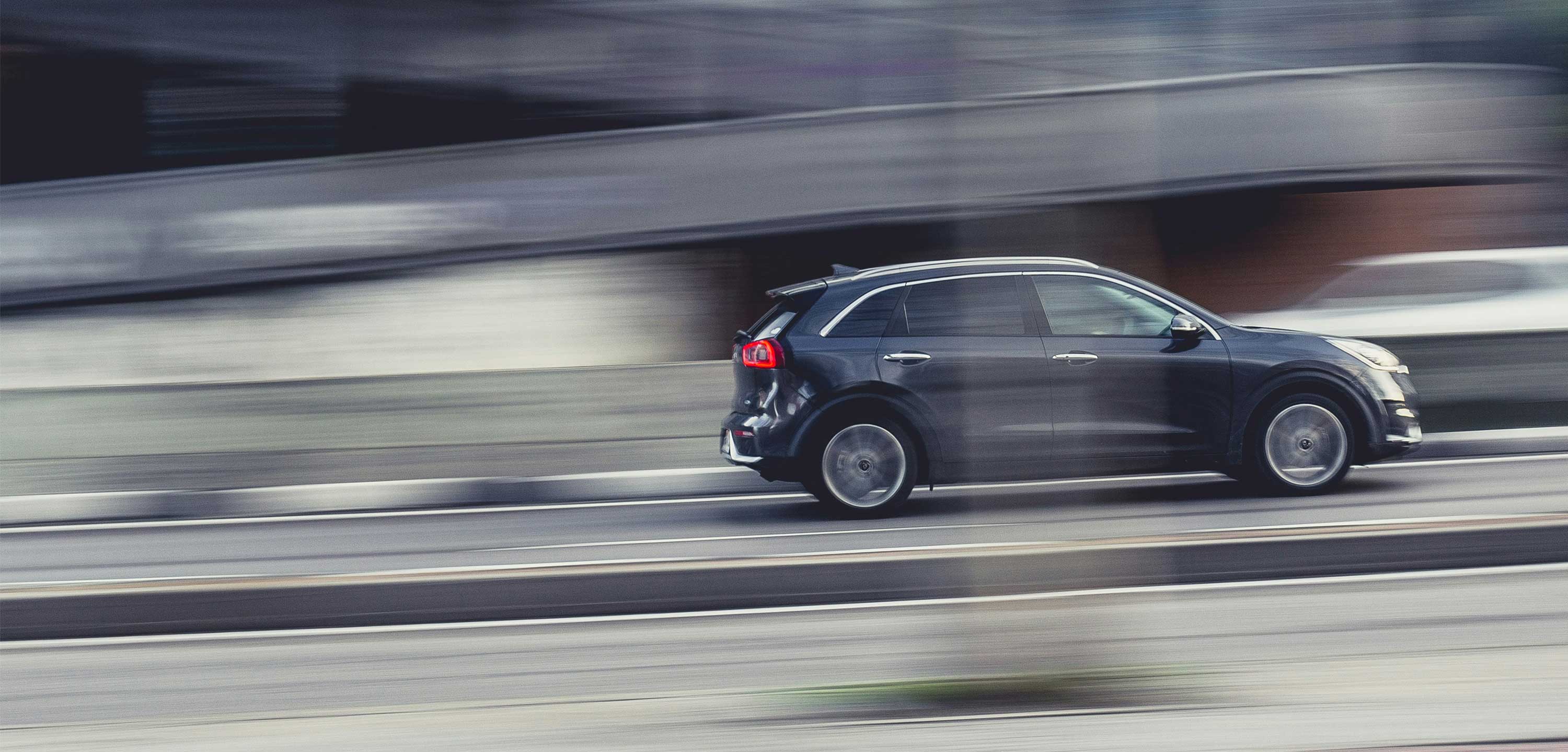 Black SUV driving rapidly on a highway with motion blur effect.