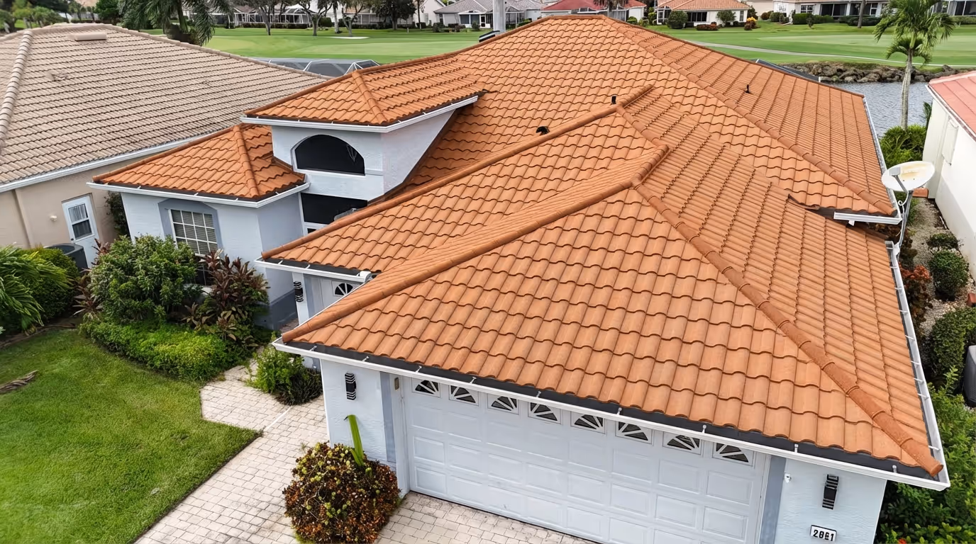 White house with terracotta tile roof, white garage door, green lawn, and landscaping.