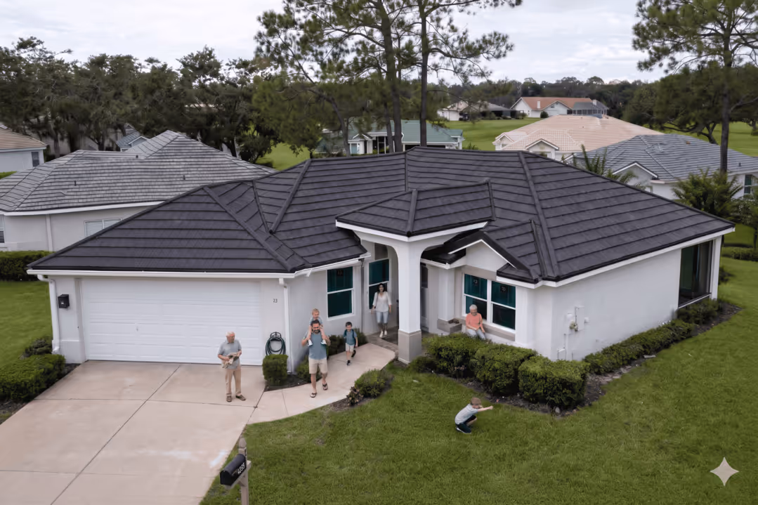 A family of seven outside a modern single-story house with a black roof and green lawn.