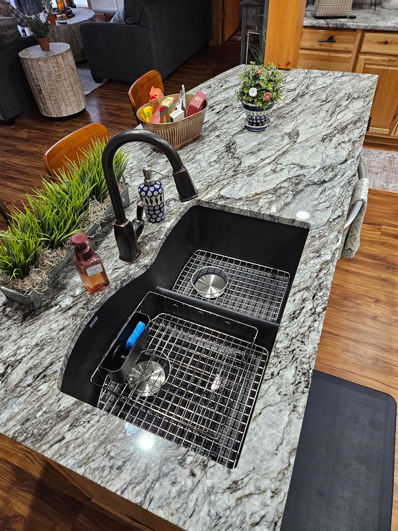 Modern kitchen sink with black faucet installed in a gray and white marble countertop.