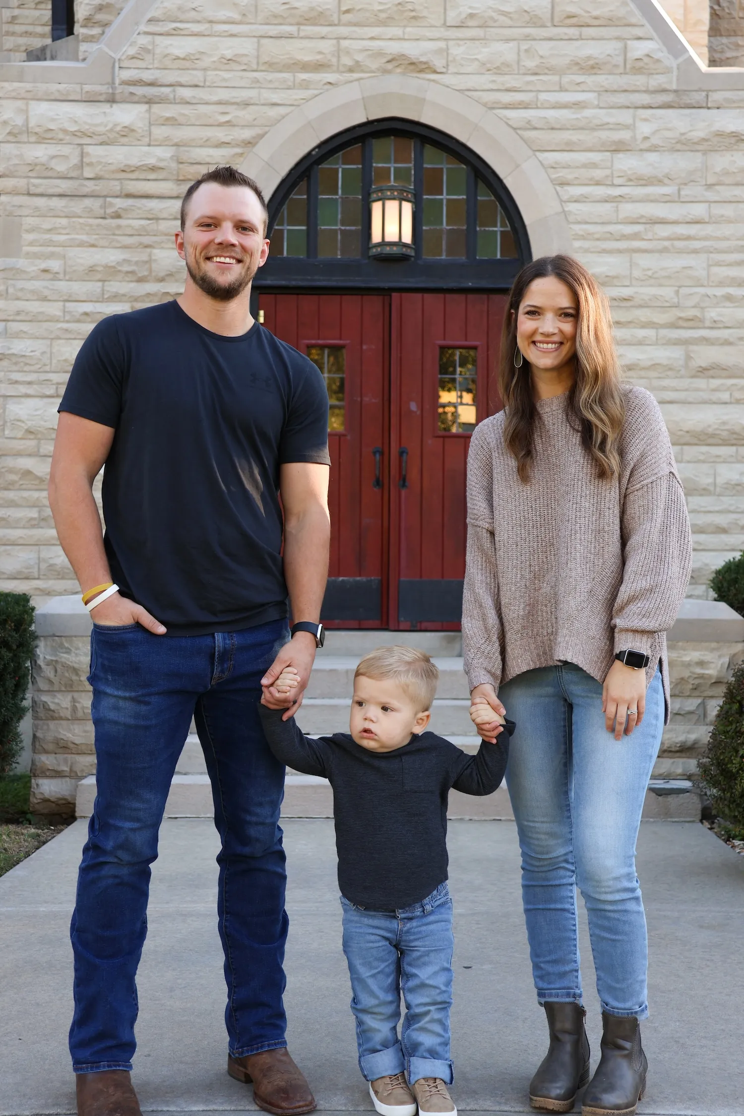 The Oliver family holding hands and smiling.
