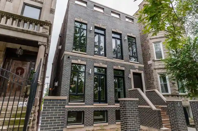 Exterior of the Campbell New Construction row home, featuring a dark brick facade and black-framed windows.