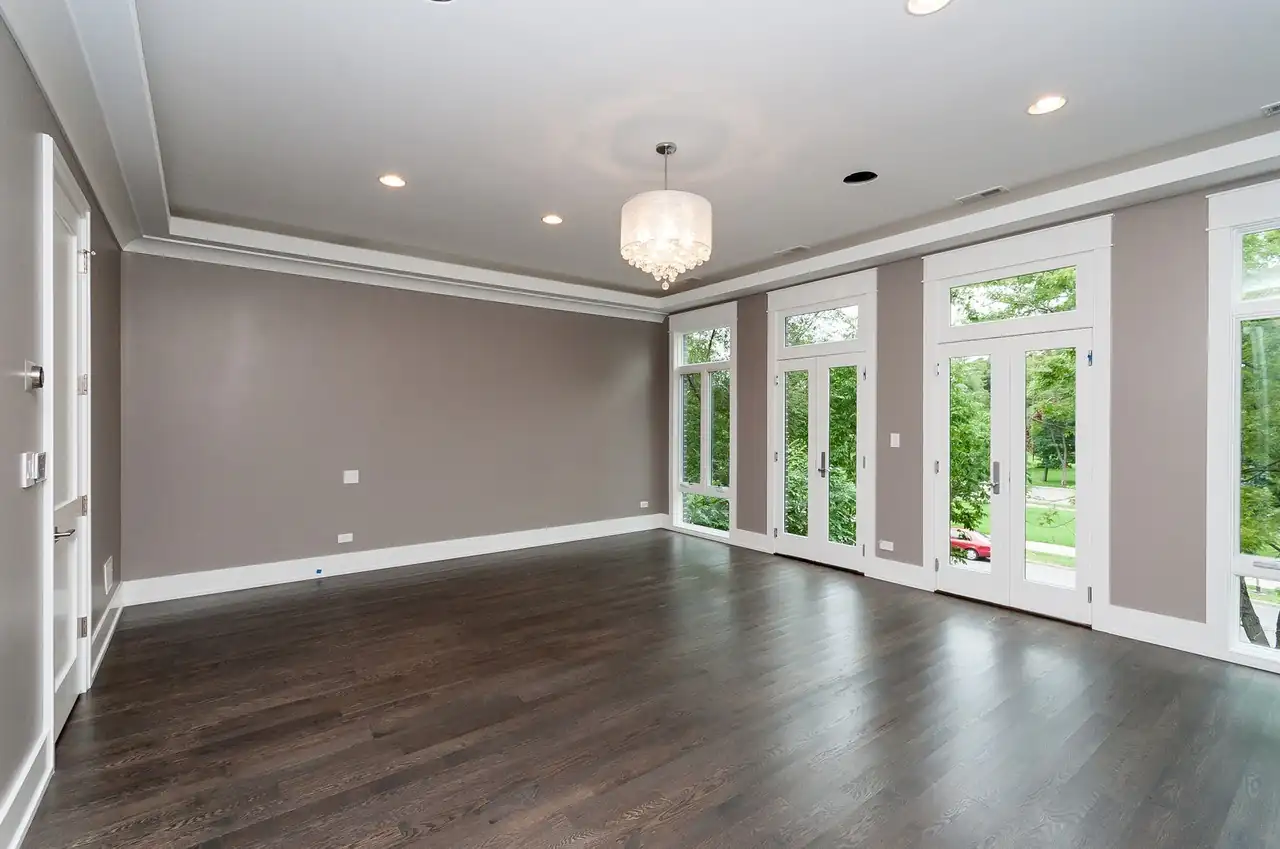 Unfurnished bedroom with taupe walls, crown molding, and a row of French doors.