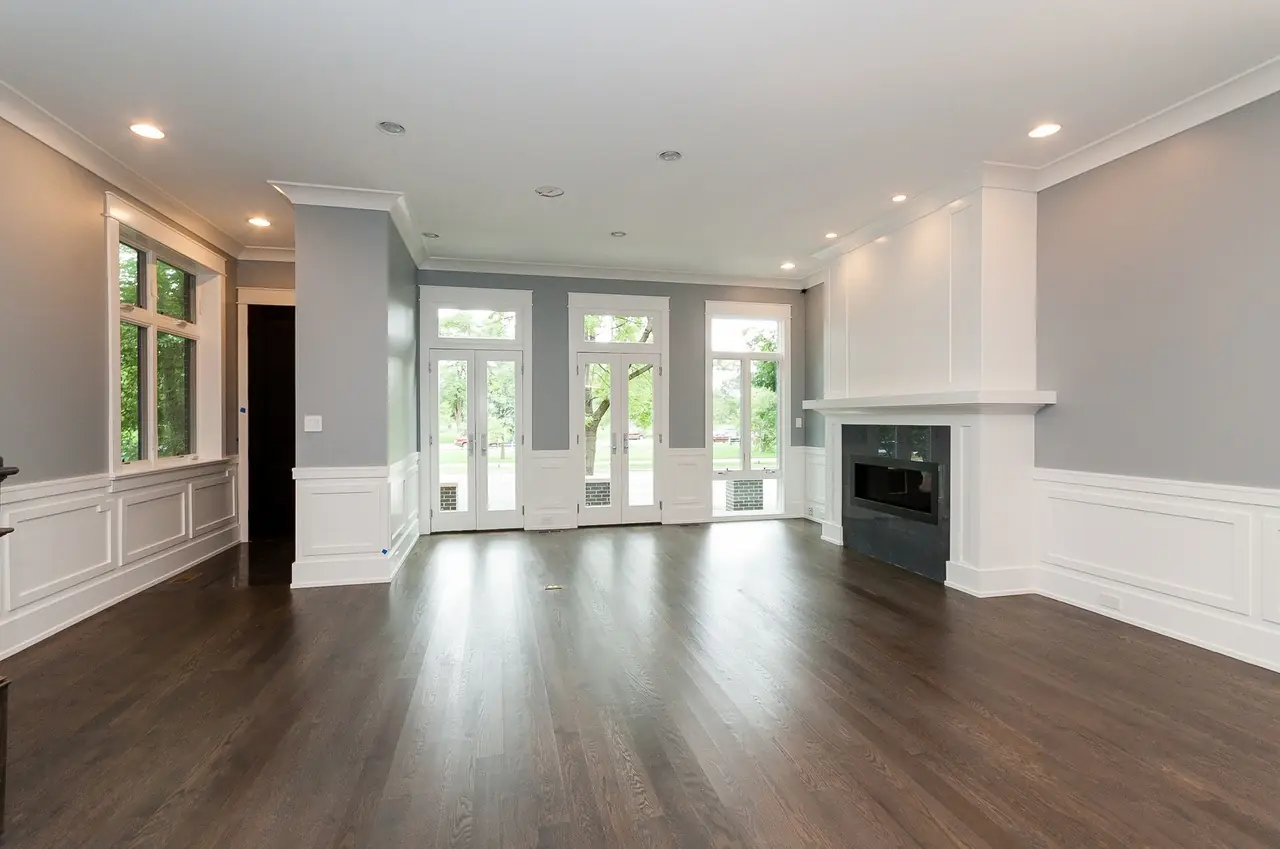 Living room corner fireplace flanked by multiple sets of French doors leading outside.