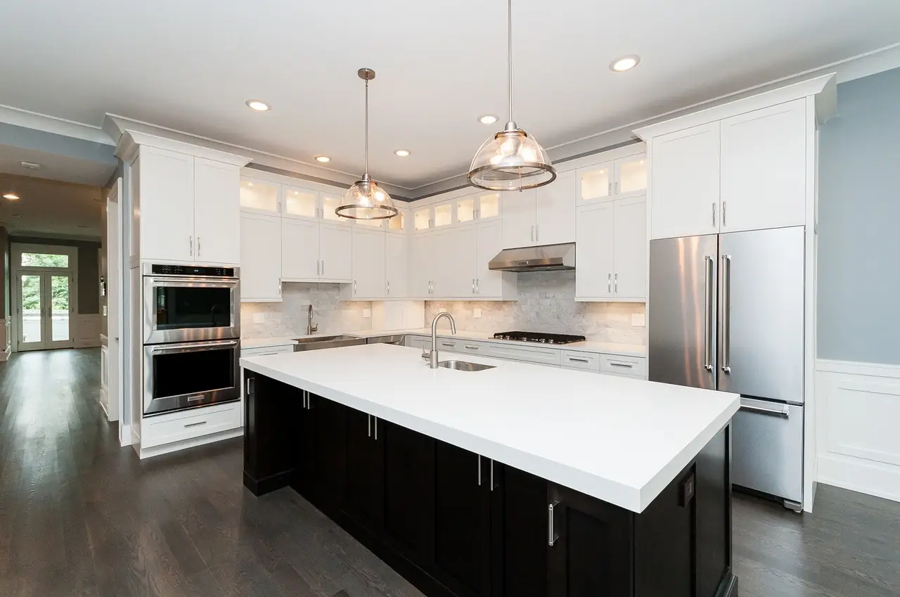 Kitchen with white shaker cabinets, a dark wood island, and stainless steel appliances.
