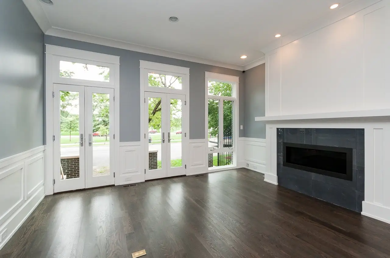 Living room with a slate-tiled fireplace and a wall of French doors overlooking the street.