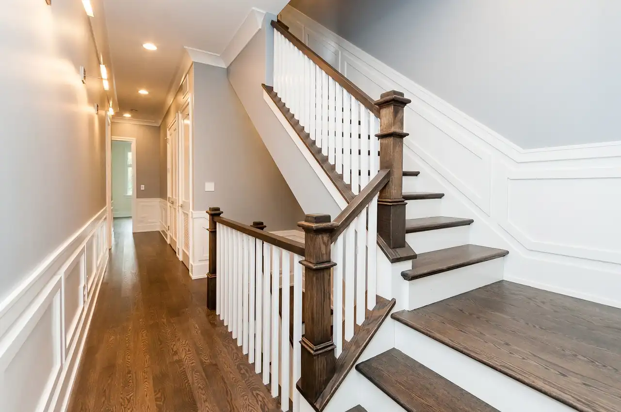 Wood and white staircase leading to a hallway in the Campbell New Construction home.