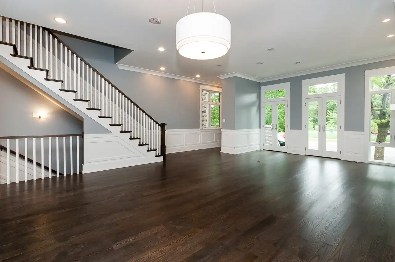 Entry foyer with a curved staircase, dark hardwood floors, and French doors leading outside.