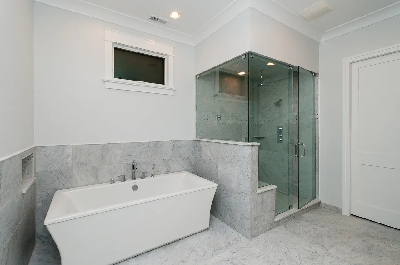 Primary bathroom with a freestanding soaking tub and a glass-enclosed marble shower.