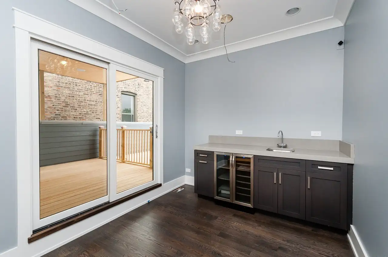 Wet bar with a beverage fridge and sink beside sliding glass doors opening onto the deck.