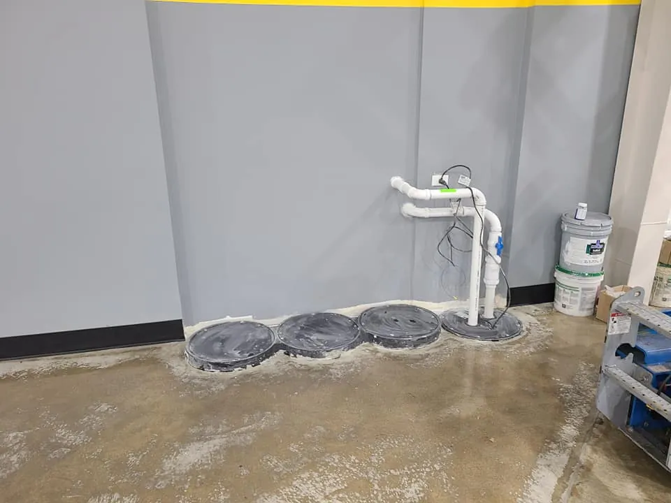 In-floor utility access covers and PVC plumbing stub-outs set into the warehouse addition's concrete slab.