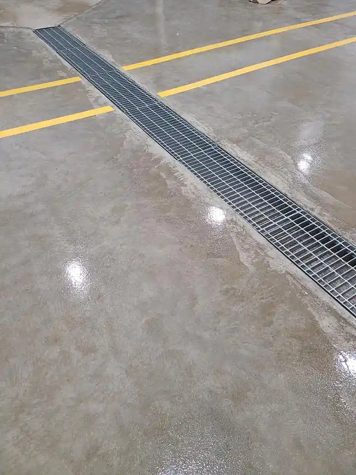 Steel trench drain grating embedded in the polished concrete floor of the warehouse addition.