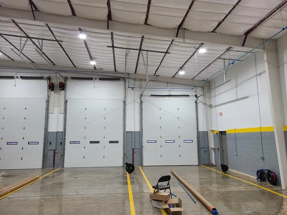 Wide interior view of dock doors, high-bay LED lighting, and painted block walls in the warehouse addition.
