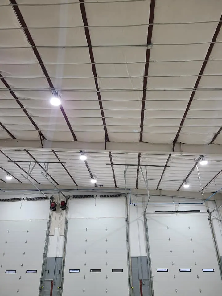 Overhead view of three sectional dock doors and exposed roof trusses inside the completed warehouse addition.