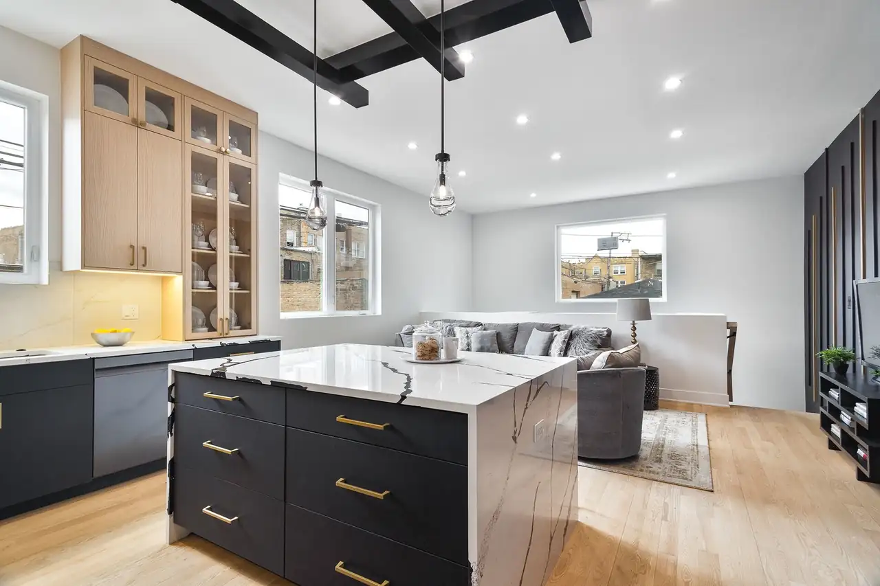 Kitchen island opens to the living room, with a black slatted accent wall, gray sectional, and rooftop views of the Chicago neighborhood.