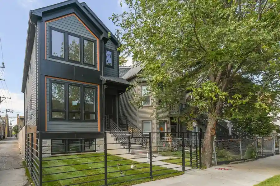 Front exterior of the Kimball New Construction home, charcoal siding with orange-trimmed windows and a black metal fence in Chicago, IL.