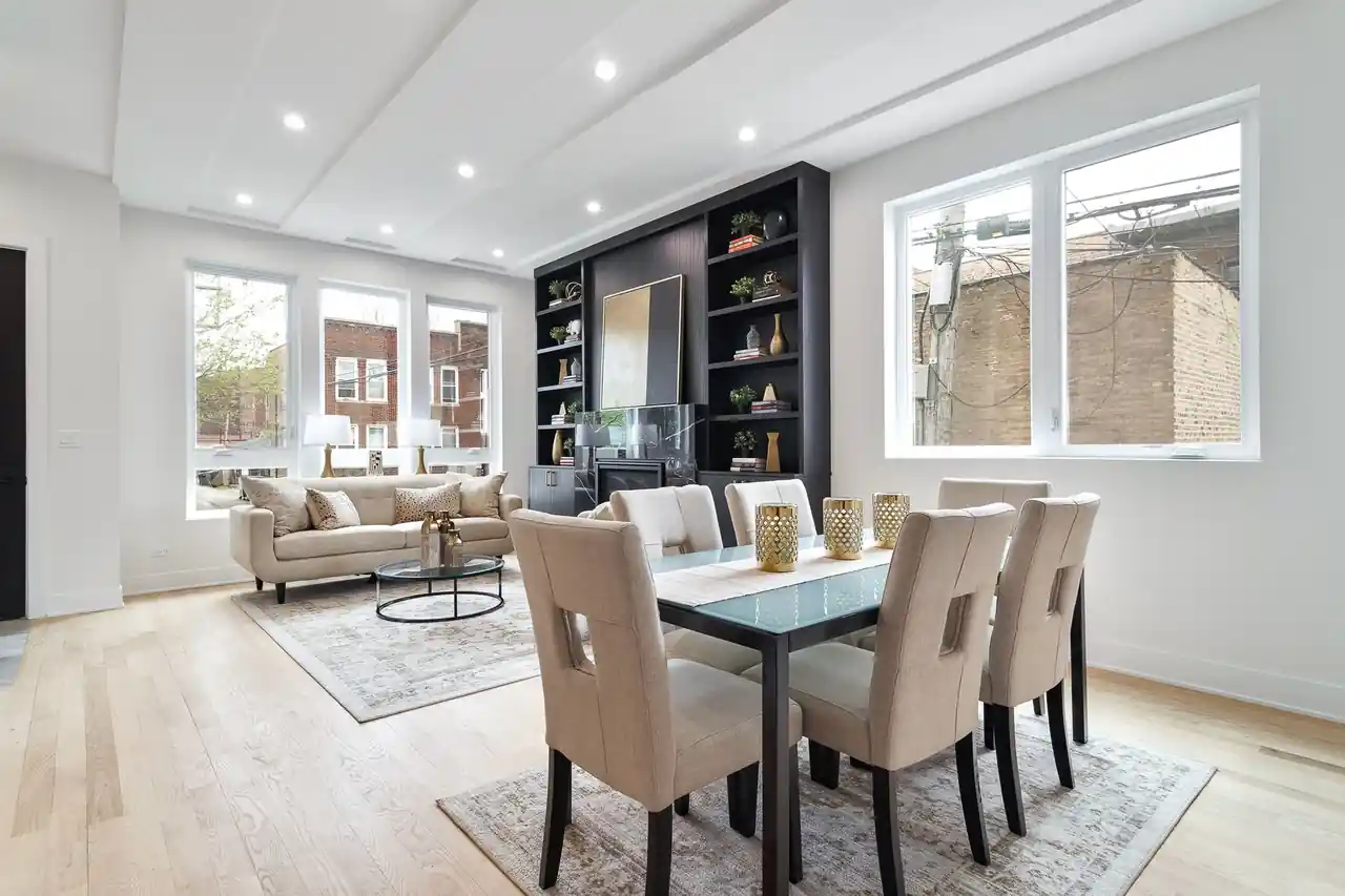 Living and dining space with a dark built-in shelving unit, large windows, and a view of Chicago's classic brick two-flats.