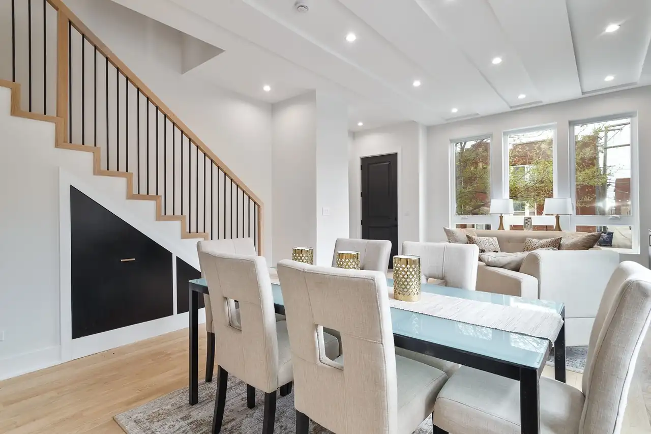 Dining area beside the staircase, featuring a wood handrail, black balusters, and built-in storage tucked beneath the steps.