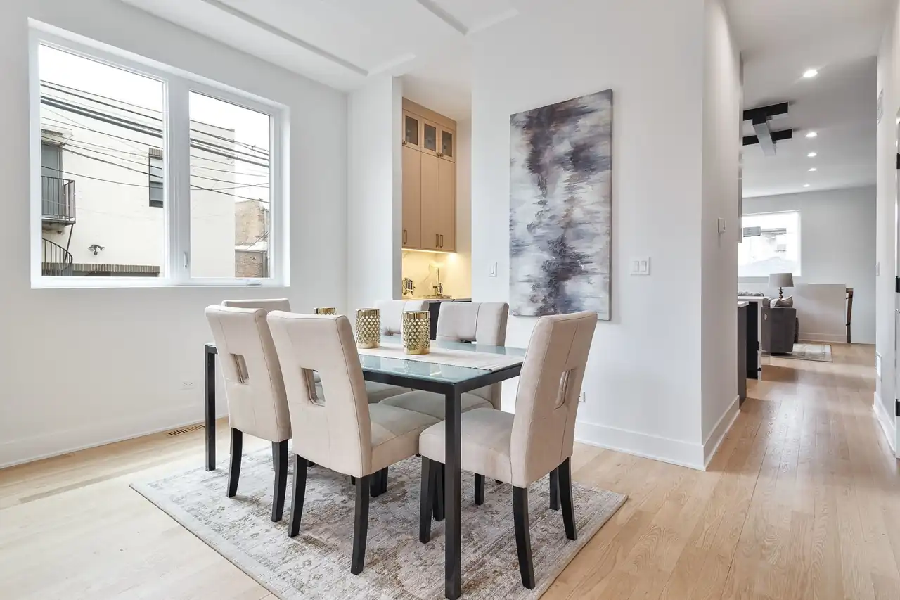 Dining nook with a glass-top table, abstract wall art, and a window overlooking the surrounding Chicago brickwork.