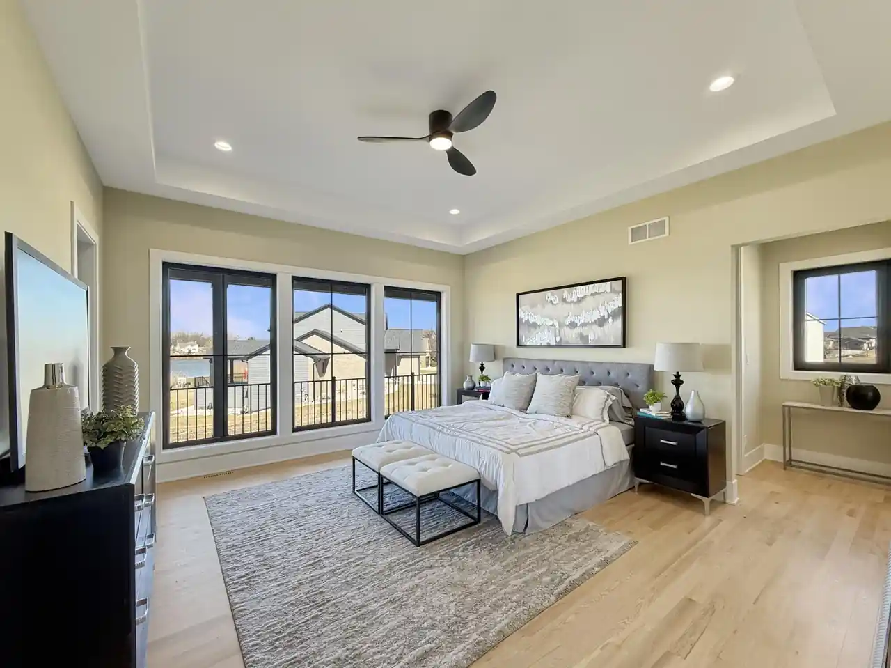 Bedroom with a tufted gray headboard and full-width windows framing the water view.