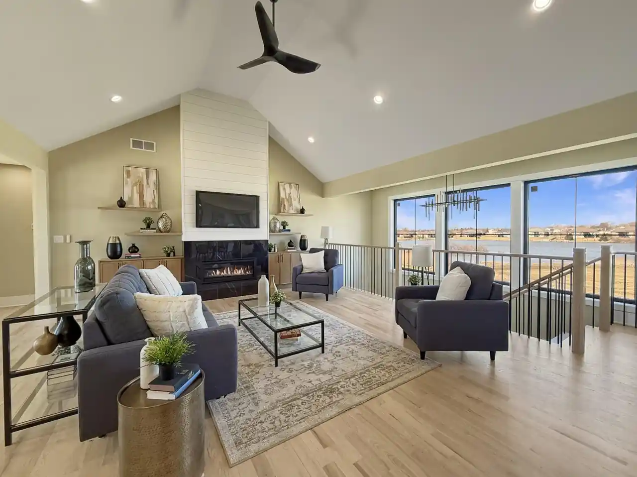 Vaulted living room with a shiplap fireplace surround and a wall of windows overlooking the lake.