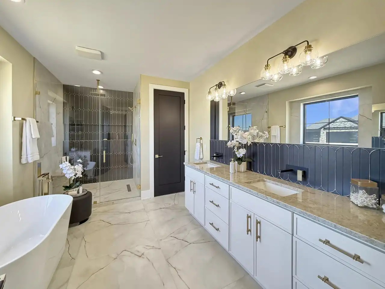 Primary bath with a dual vanity, scalloped blue tile backsplash, and a glass-walled rain shower.
