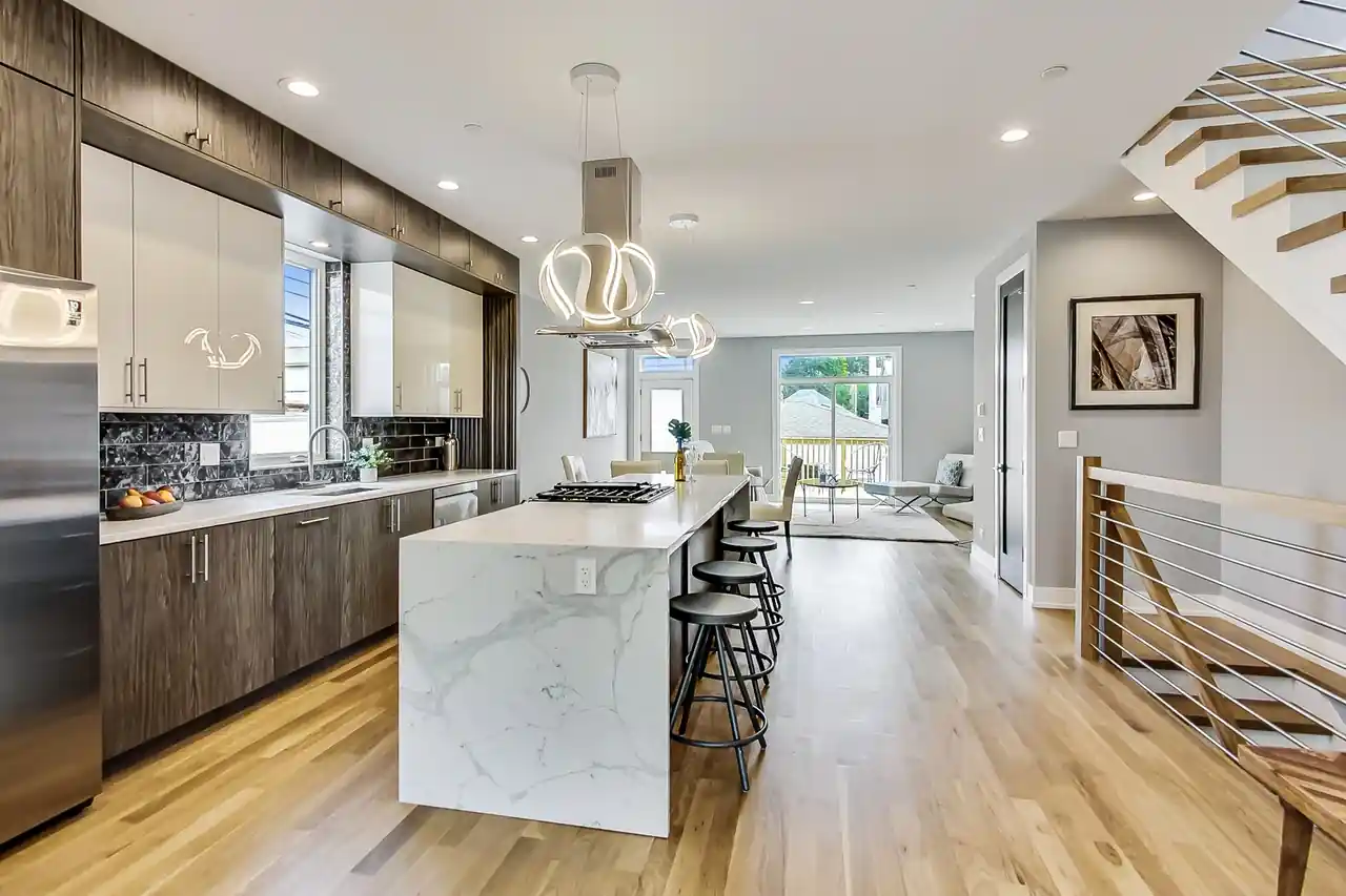 Kitchen island with waterfall marble countertop and sculptural ring pendants in the New Castle New Construction kitchen.