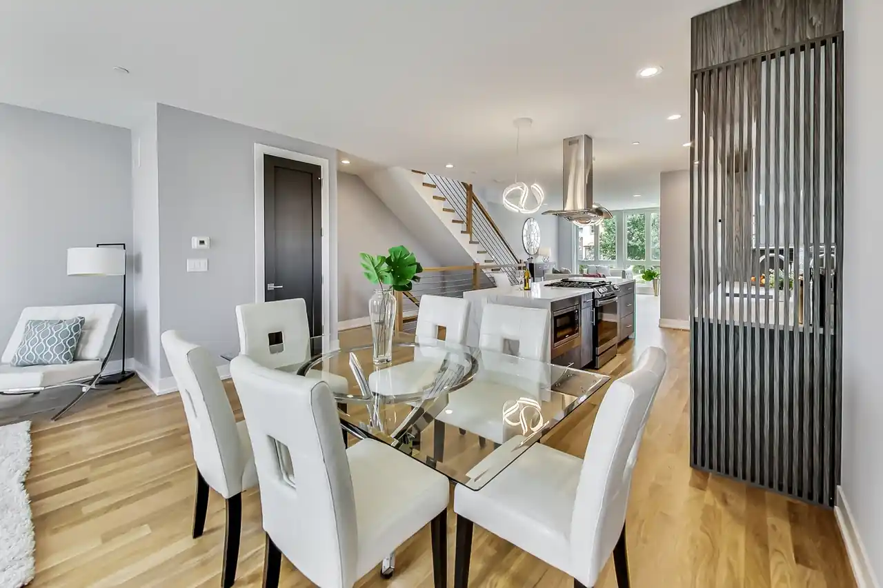 Open dining area with a glass-top table for six, a wood slat privacy screen, and a view into the kitchen.