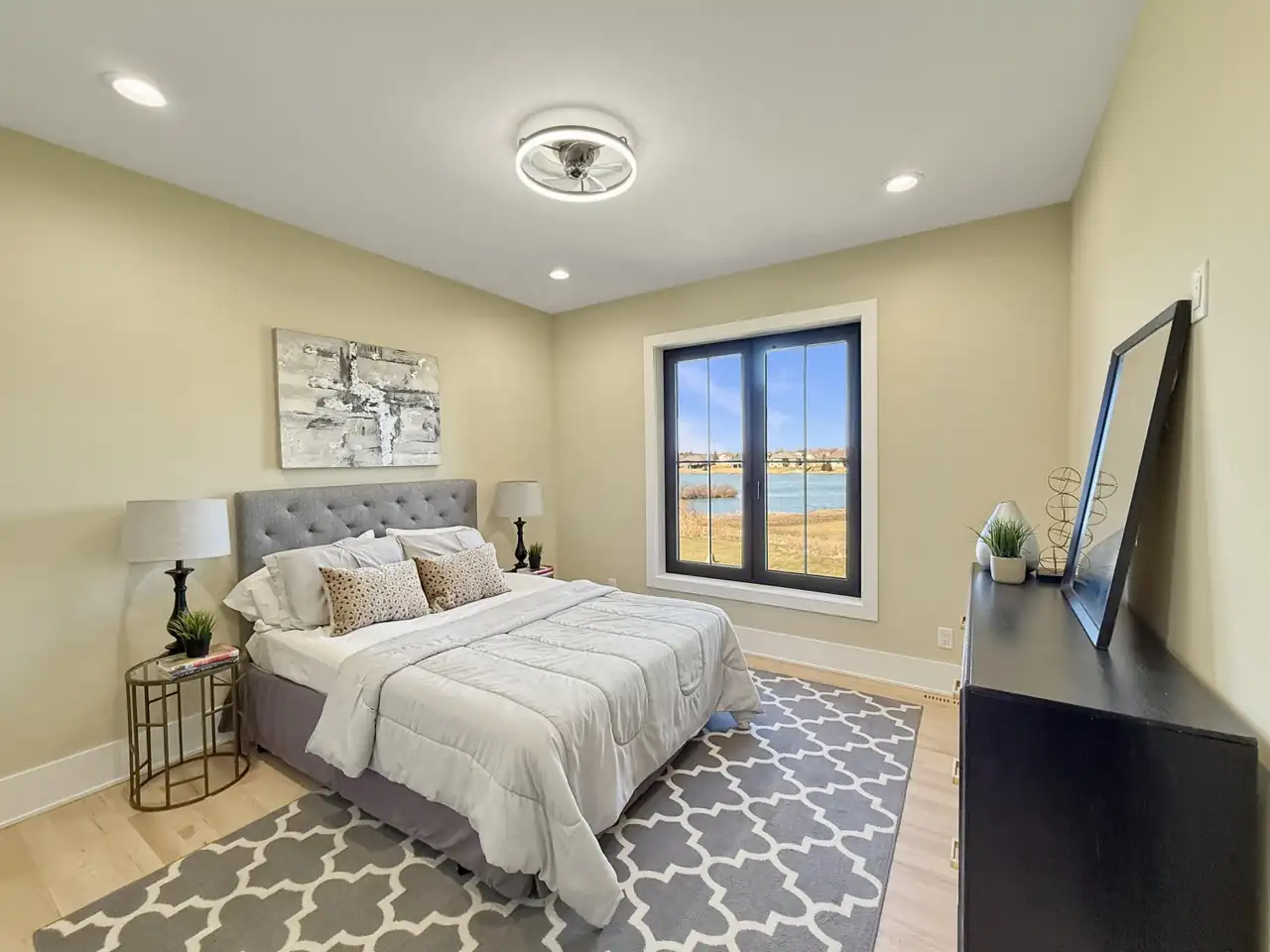 Guest bedroom with a quatrefoil-pattern rug and a window overlooking the water.