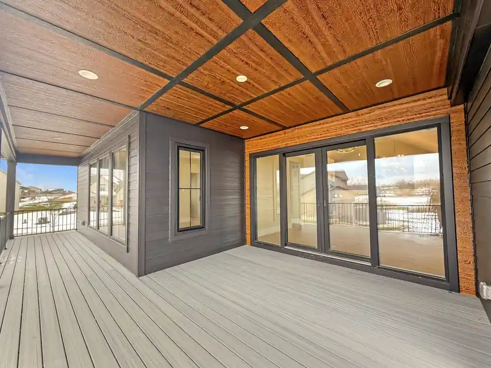 Lower covered patio with a wood-panel ceiling and full-glass sliding doors to the walkout level.