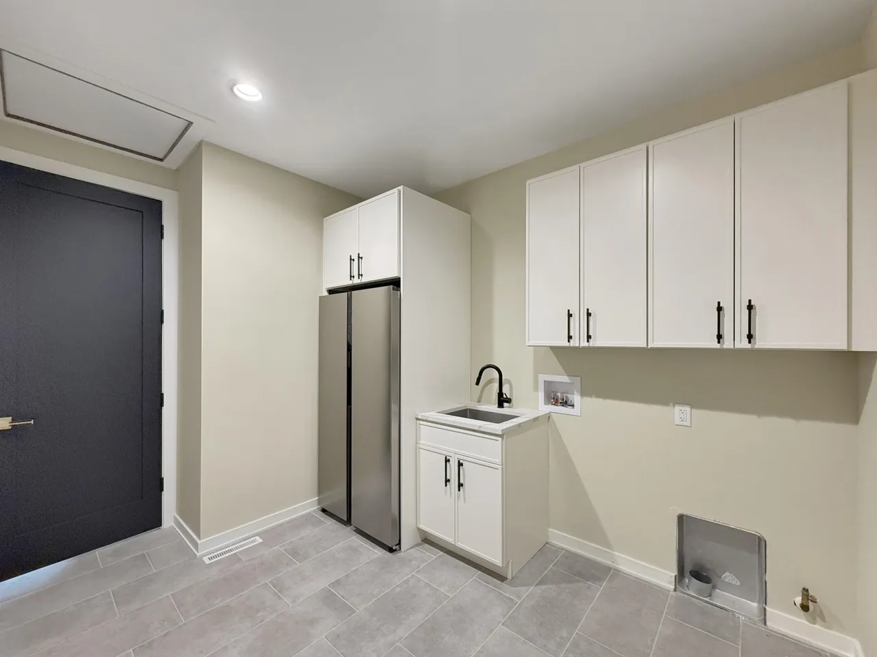 Butler's pantry with a utility sink, white cabinetry, and a stainless-steel refrigerator.