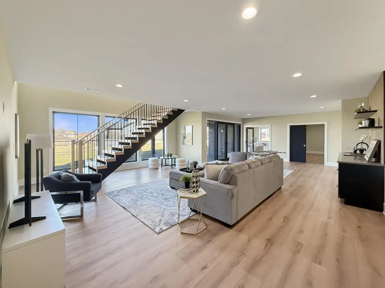 Lower-level living space with a floating staircase and doorways to additional finished rooms.
