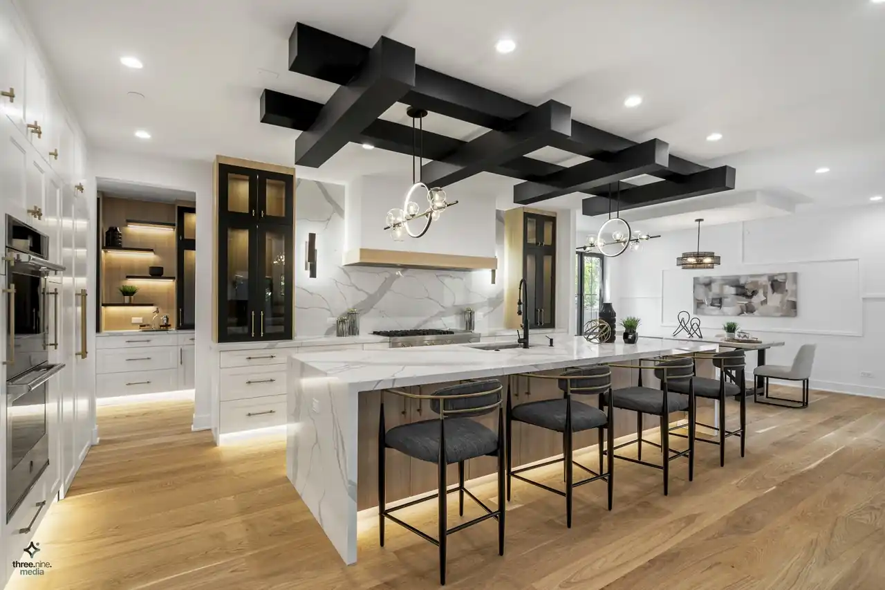 Wide kitchen view with wood-toned cabinetry, brass pendant lighting, and marble backsplash