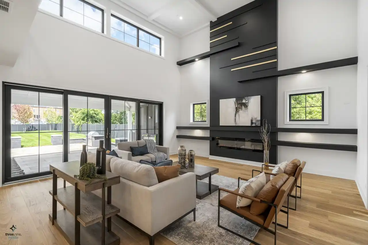 Two-story great room with a linear black feature wall and floor-to-ceiling sliding glass doors