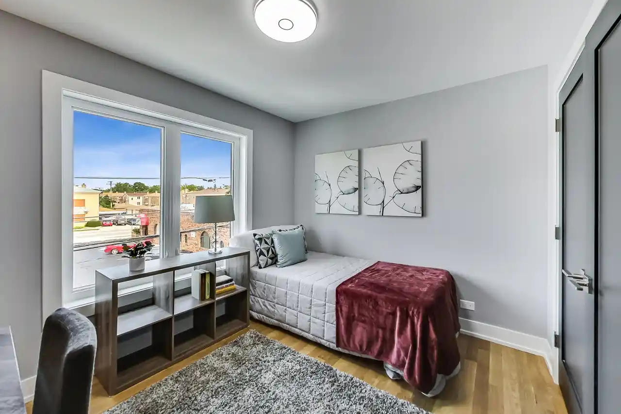 Guest bedroom with a daybed, a pair of botanical line-art panels, and a street-facing window.