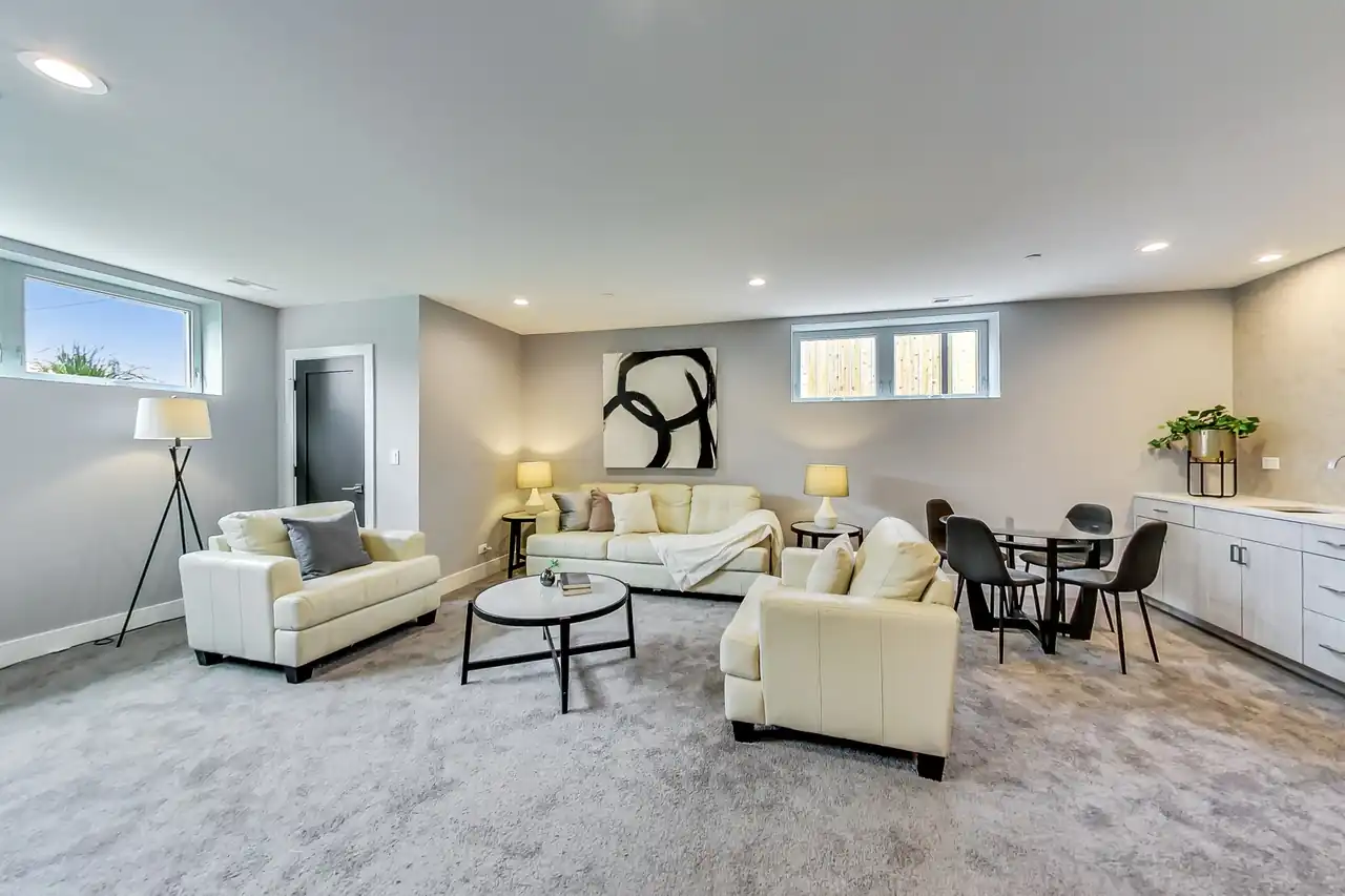 Finished lower-level rec room with cream leather seating, a dining nook, and a wet bar.