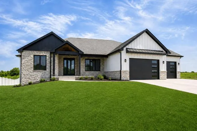 Front exterior view showing the home's dual gables, stone and white siding, and a paver walkway to the covered porch.