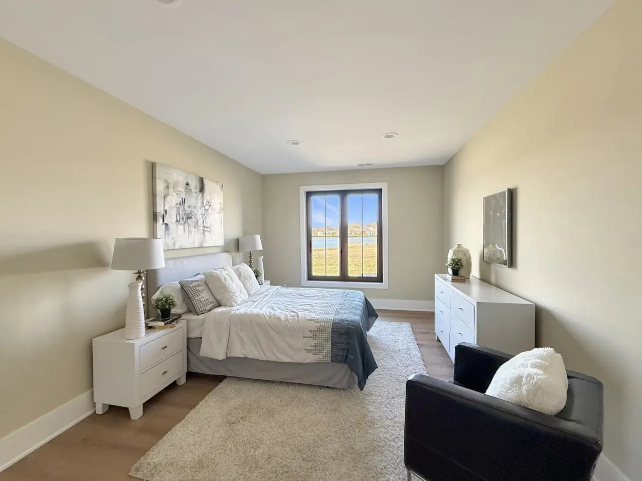 Bedroom with layered gray-and-white bedding and a window looking out over the water.
