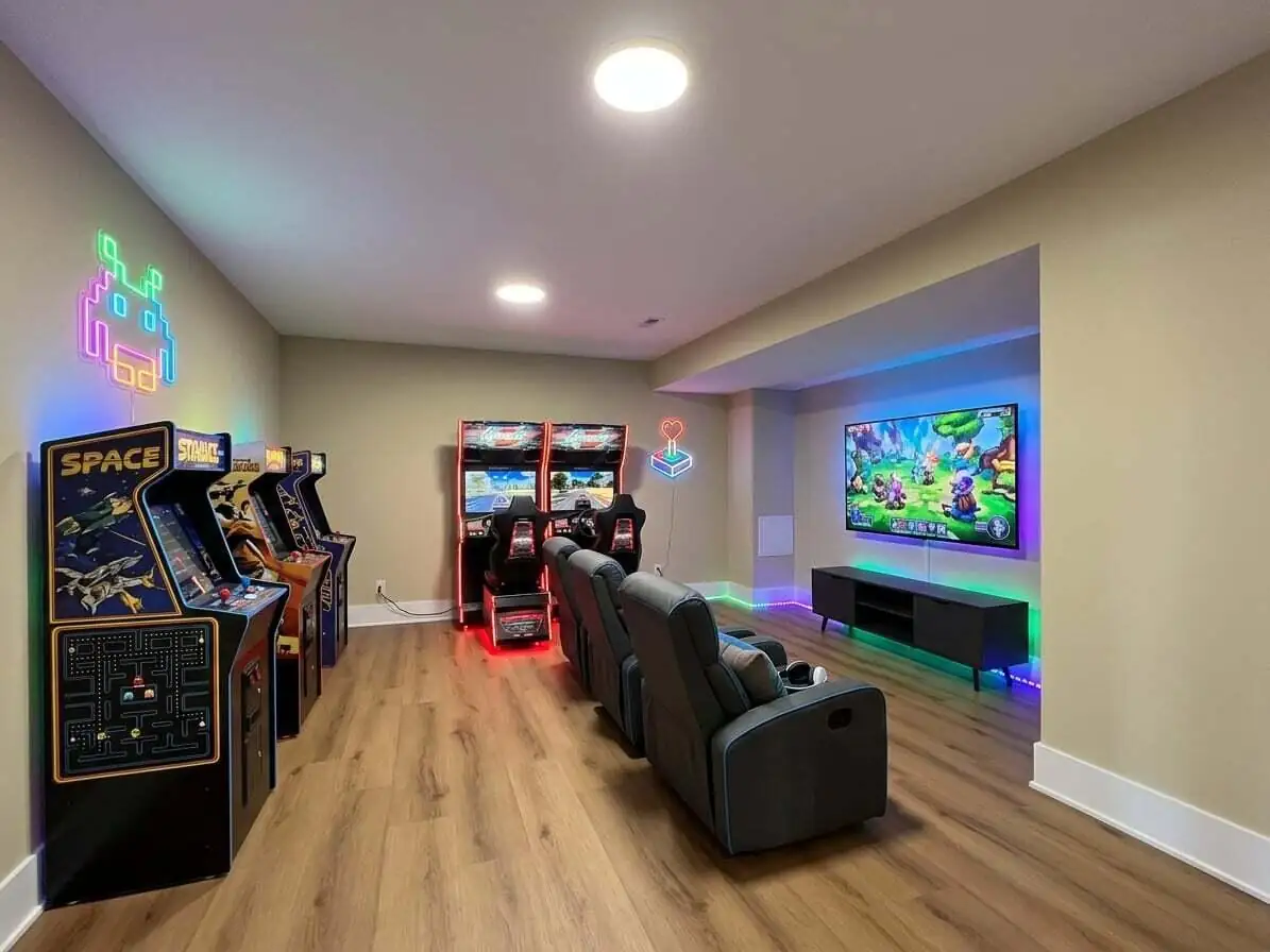 Arcade room lined with classic cabinet games and neon signage beneath a mounted TV.