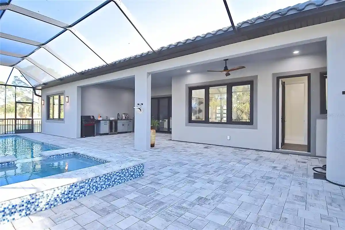 Screened lanai with pool, spa, and outdoor kitchen along the rear of the home.