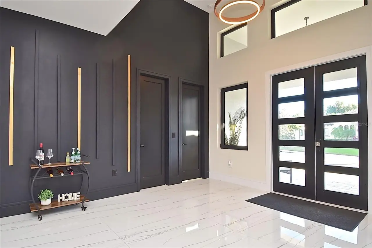 Two-story entry hall with a black accent wall, wine cart, and ring pendant light.