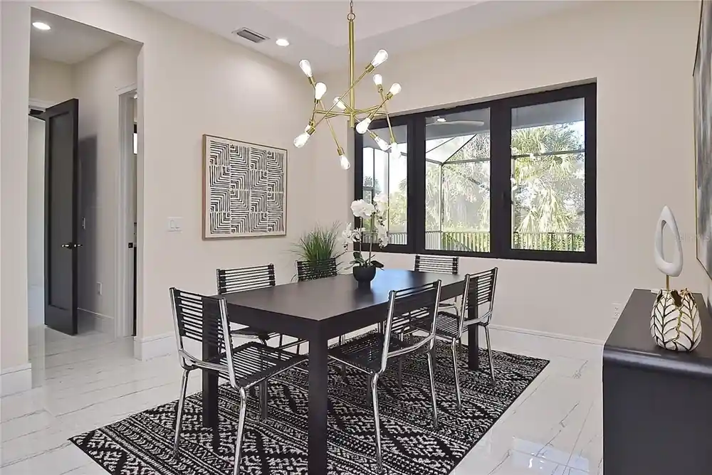 Dining nook with a matching table and chandelier, windows opening to the screened lanai.